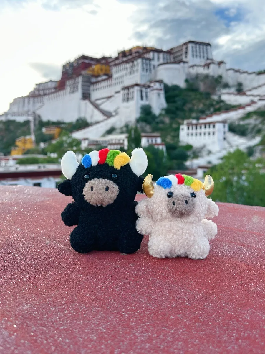 Tashi and Dele on a red rooftop ledge with the Potala Palace right behind them — 布達拉宮前的扎西與德勒（近）